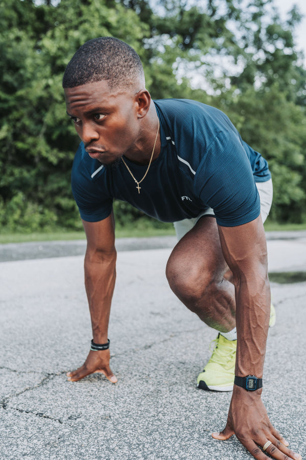 Person stretching outdoors on a paved path with greenery in the background